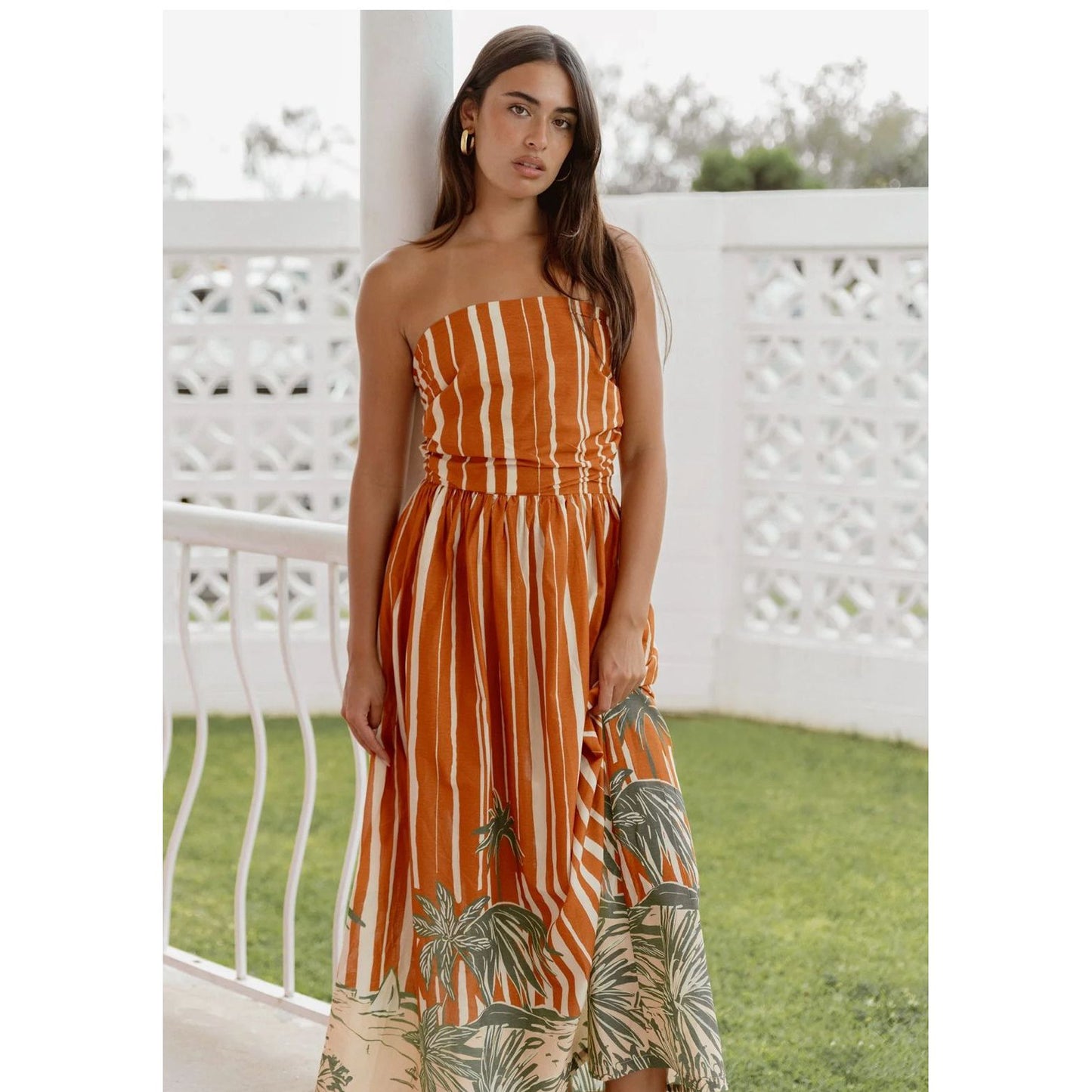 Woman wearing a strapless orange and white striped mina maxi dress