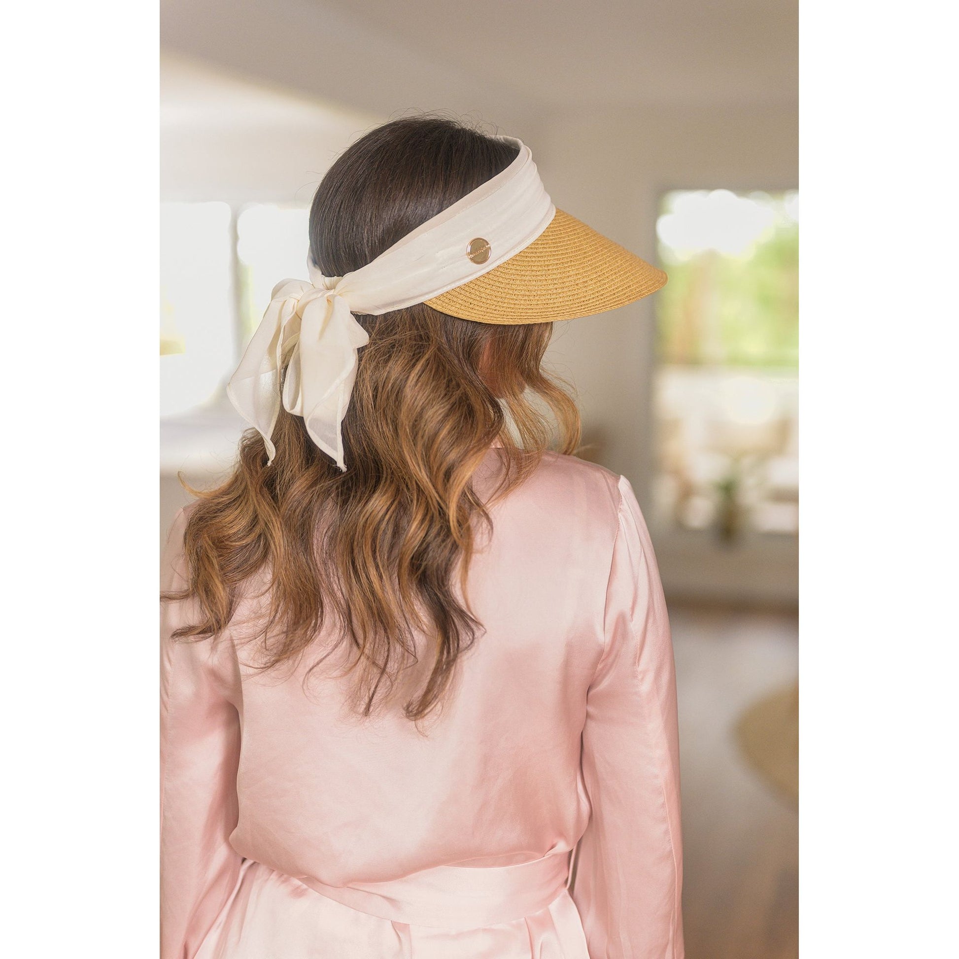 Woman wearing a visor with a bow in an indoor setting