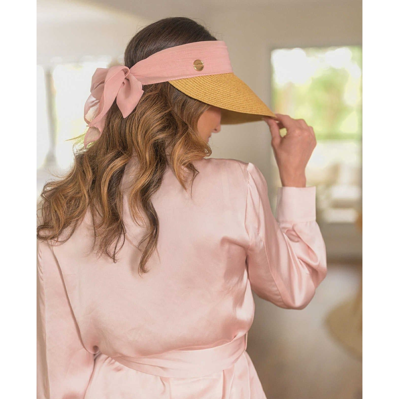 Woman wearing a pink visor with a large bow and a yellow sun visor.