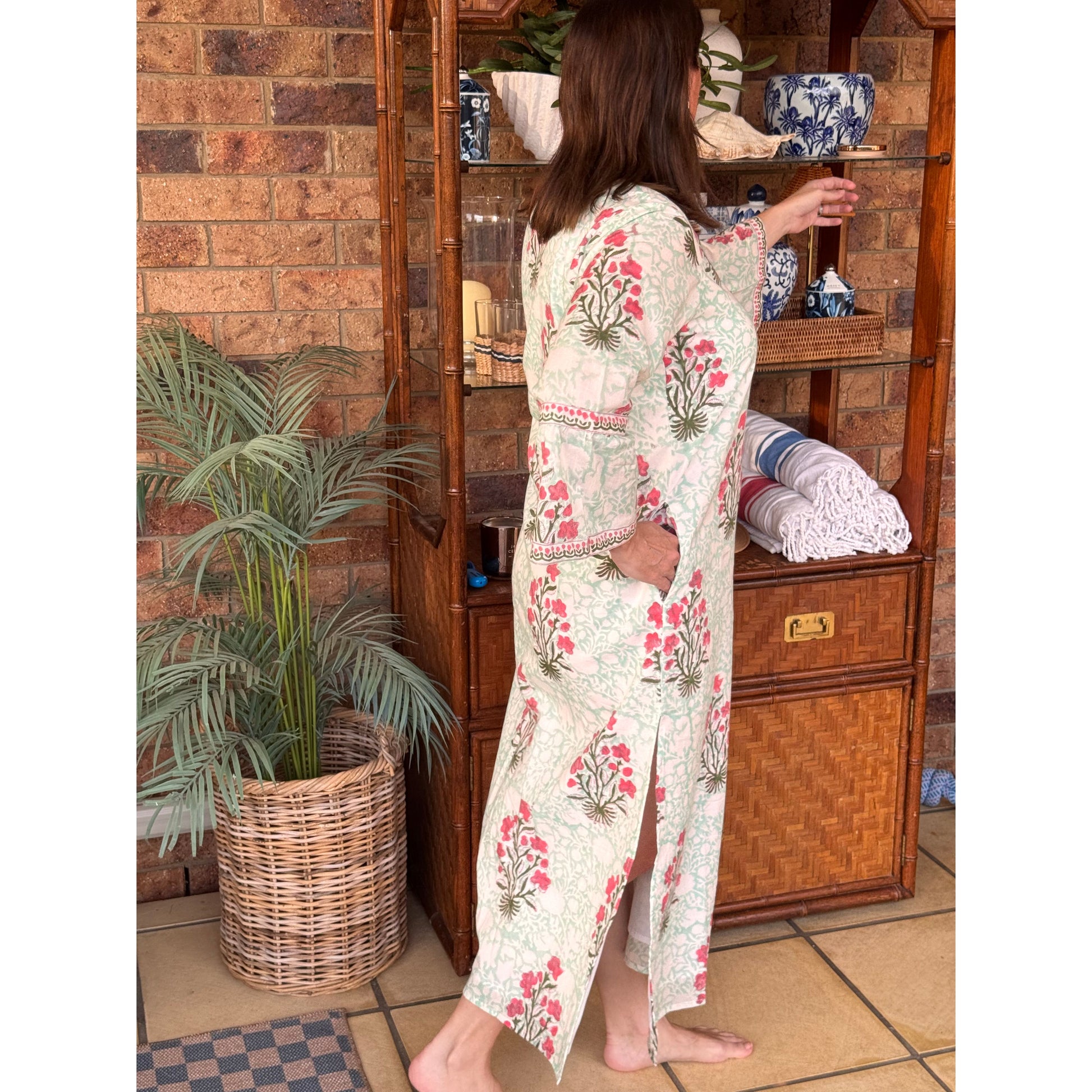 Person wearing a floral dress lying on a wooden floor with a plant in the foreground.